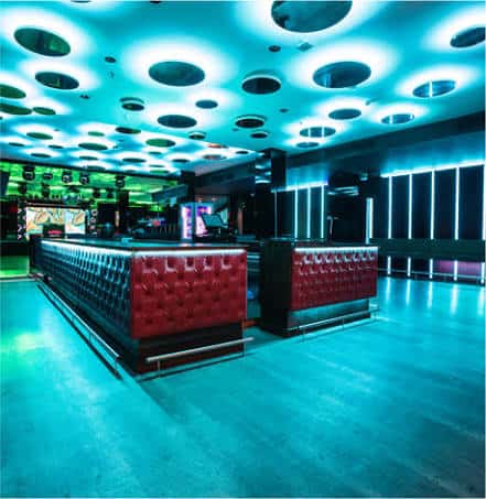 Interior del club con barra de cuero rojo y techo iluminado en azul