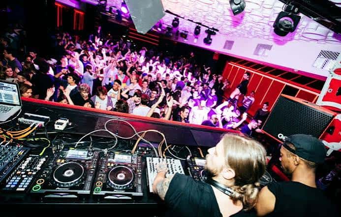 Vista desde la cabina de DJ con multitud bailando bajo luces de fiesta