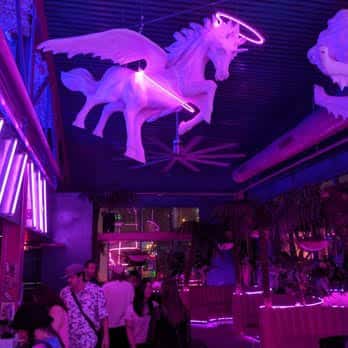 Decoración interior con unicornio alado colgando del techo entre luces neón