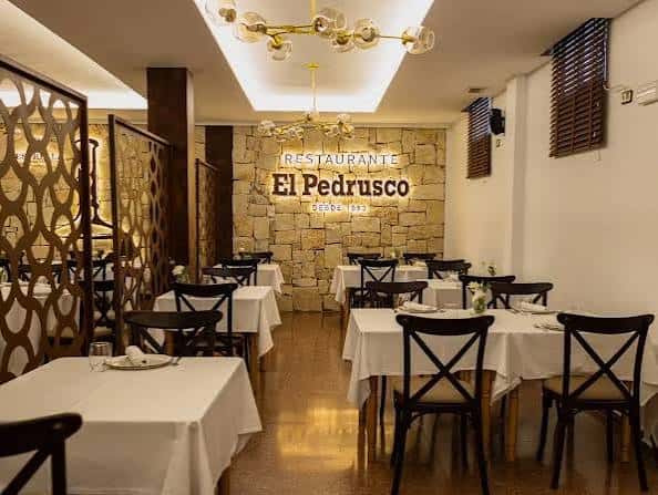 Interior del restaurante El Pedrusco con mesas dispuestas y decoración moderna