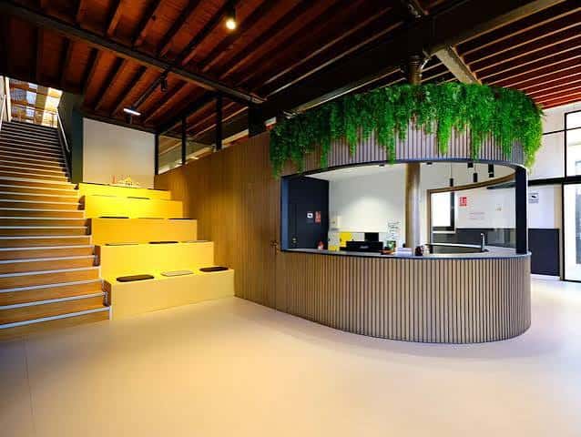 Interior del centro con recepción circular, escalera iluminada y techo de madera