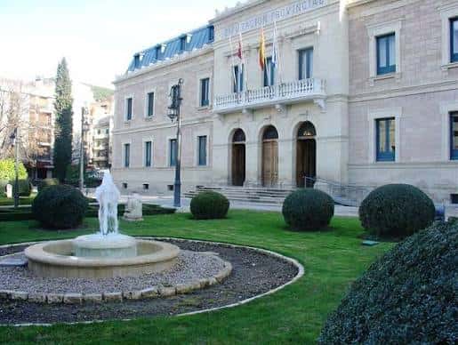 Vista lateral del edificio con fuente en primer plano y jardines bien cuidados