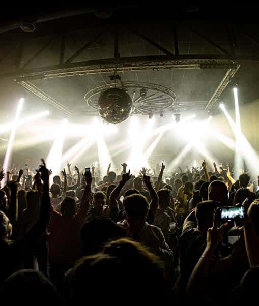 Vista desde el público hacia el escenario con luces y bola disco en el Industrial Copera