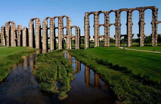 Acueducto reflejado en el río Guadiana bajo un cielo despejado