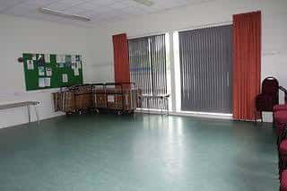 Sala principal del centro comunitario con suelo verde y cortinas rojas
