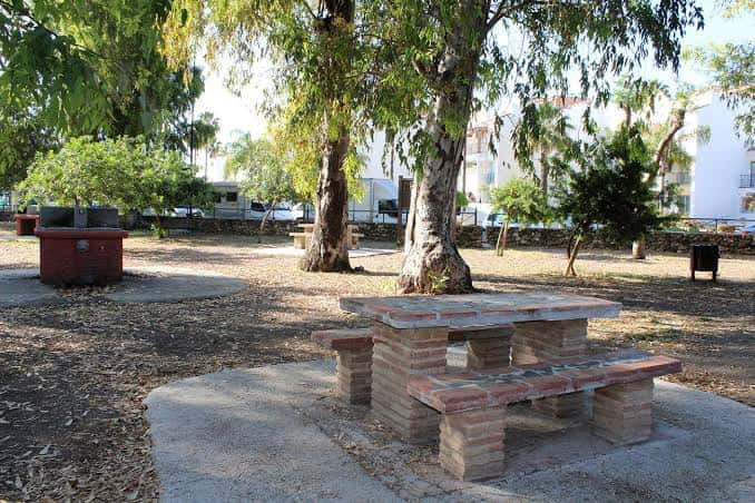 Zona de picnic con mesas de ladrillo bajo árboles en el parque