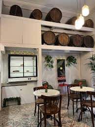 Interior del Santuari Coffee con mesas redondas y decoración de barriles de madera