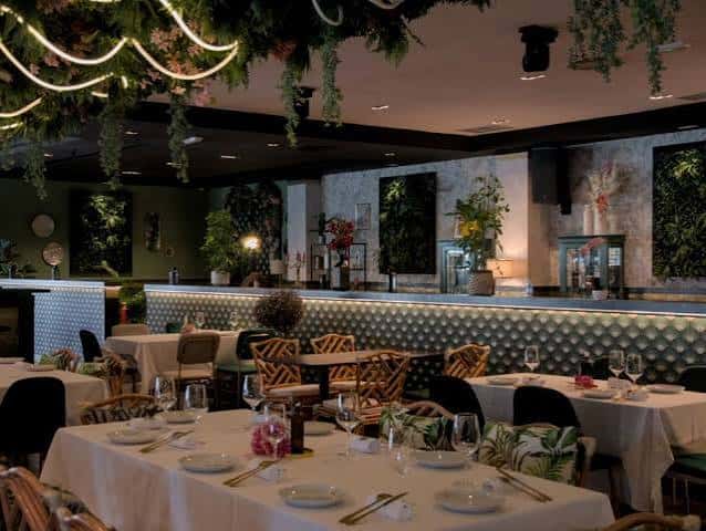 Interior elegante del restaurante con decoración botánica y mesas dispuestas para cena