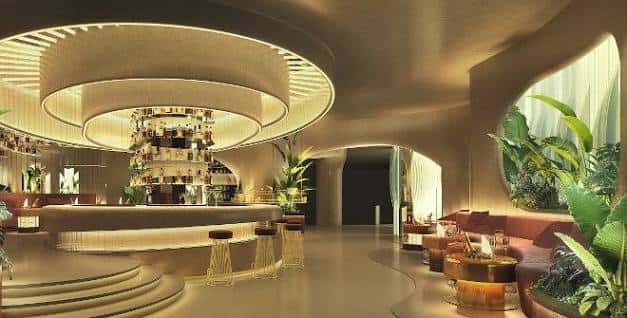 Interior elegante del Fitz Club con barra central iluminada, mobiliario moderno y decoración orgánica