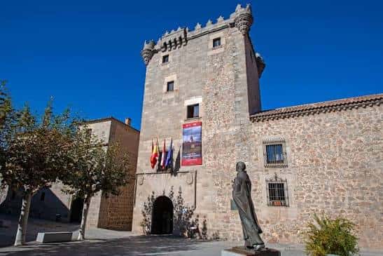 Fachada principal del palacio bajo cielo azul con escultura en primer plano