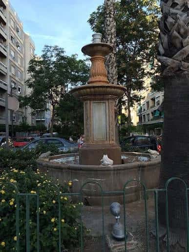 Fuente ornamental en la plaza rodeada de vegetación y edificios residenciales