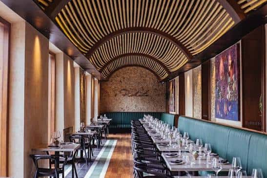 Interior elegante del restaurante con techo de madera curvado y mesas dispuestas para cena