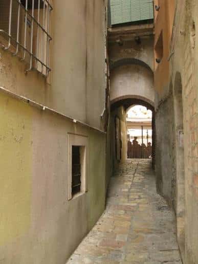 Vista del estrecho callejón empedrado con arcos y edificios de fachadas antiguas