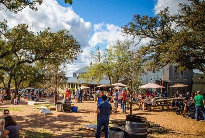 Vista exterior del patio de Jester King Brewery con invitados disfrutando en mesas al aire libre