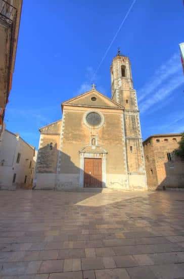 Vista frontal de la Parròquia de Santa Maria de la Geltrú con su fachada clásica y campanario bajo un cielo azul