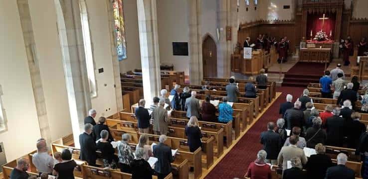 Interior del templo durante un servicio con congregación en los bancos y coro en el altar