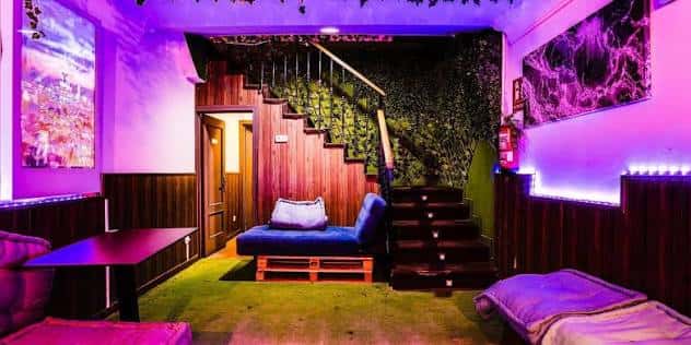 Zona de descanso interior con sofás, escalera de madera y paredes verdes