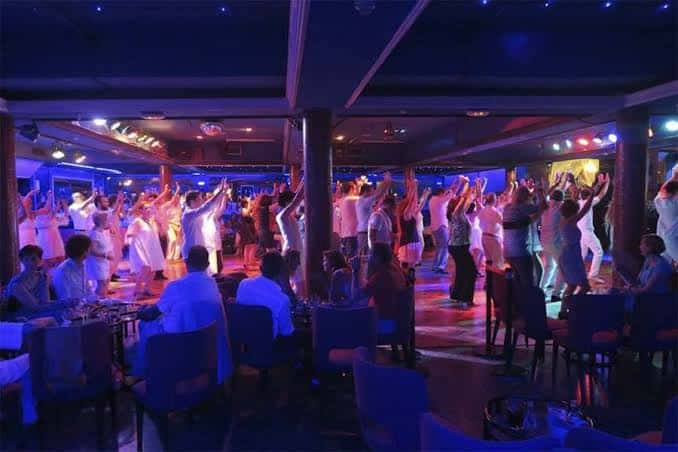 Grupo de bailarines levantando los brazos en sincronía durante una clase o sesión social de baile