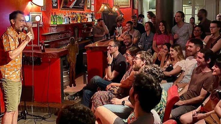 Espectáculo de stand-up comedy con público sentado y bar al fondo