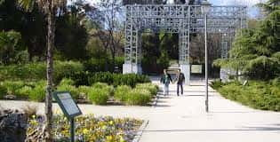Entrada principal con estructura metálica y senderos peatonales en el parque