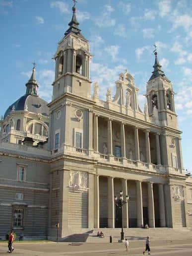Vista frontal de la Catedral de la Almudena con su fachada neoclásica y torres gemelas bajo cielo azul