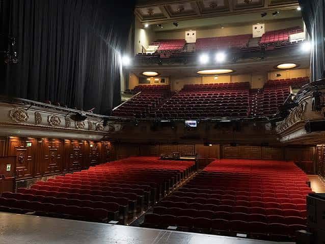 Interior del auditorio con butacas rojas y escenario desde la perspectiva del público