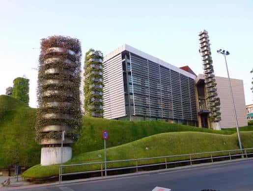 Vista exterior del Teatro del Bosque con su característica fachada de vidrio y estructuras verticales cubiertas de vegetación
