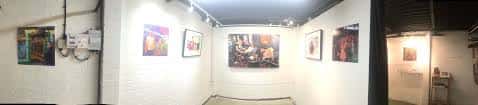 Vista panorámica del interior de la galería con paredes blancas y obras expuestas