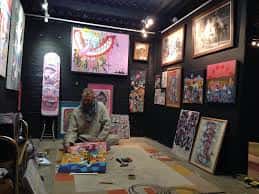 Artista trabajando en su obra dentro de la galería durante un evento