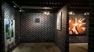 Espacio expositivo con pared de ladrillo negro y piezas de arte contemporáneo