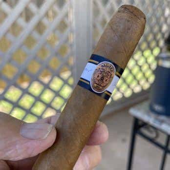 Primer plano de un cigarro artesanal sostenido en mano, mostrando su etiqueta y textura