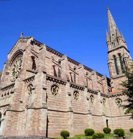 Vista lateral de la Iglesia de Nuestra Señora de la Asunción con su torre y fachada de piedra bajo cielo azul