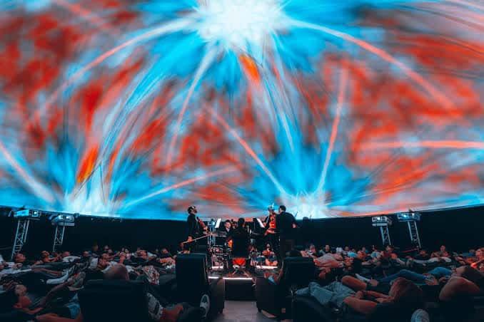 Concierto en el interior del domo con proyección visual y público recostado