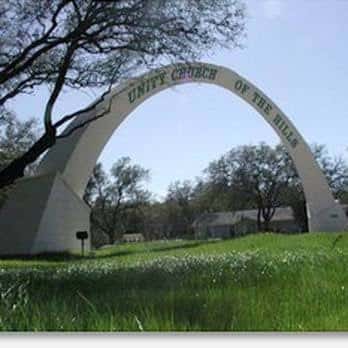 Arco de entrada con el nombre 'Unity Church of the Hills' sobre un jardín verde