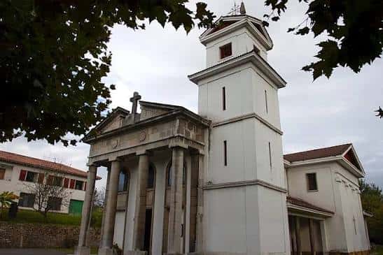 Fachada principal de la iglesia en estilo neoclásico con columnas y torre blanca