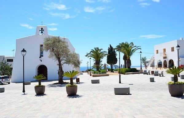 Plaza del pueblo de Sant Joan con la iglesia blanca y el mar al fondo