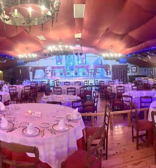 Interior del tablao con mesas dispuestas para cena y escenario iluminado