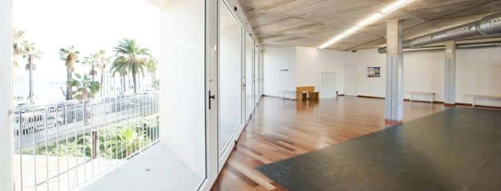 Sala de eventos vacía con suelo de madera y vistas al mar