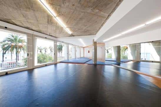 Gran salón con techo de hormigón y ventanales abiertos al balcón