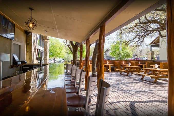 Interior y terraza de Hops & Thyme mostrando mesas de picnic y barra