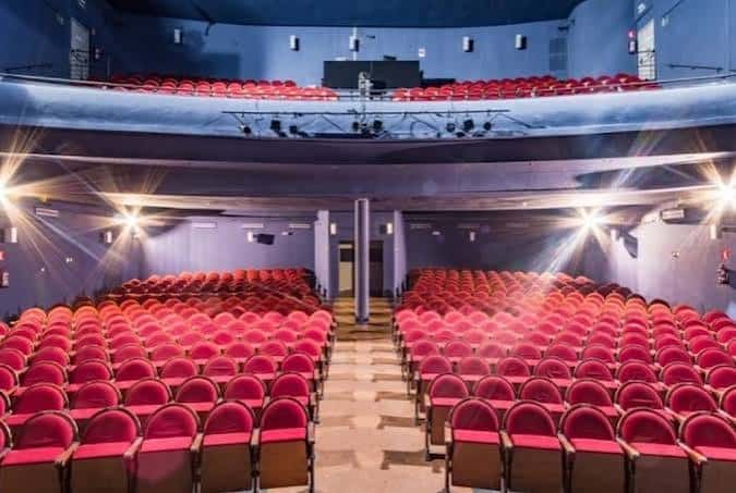 Interior del auditorio del Teatro Pavón con butacas rojas y escenario iluminado