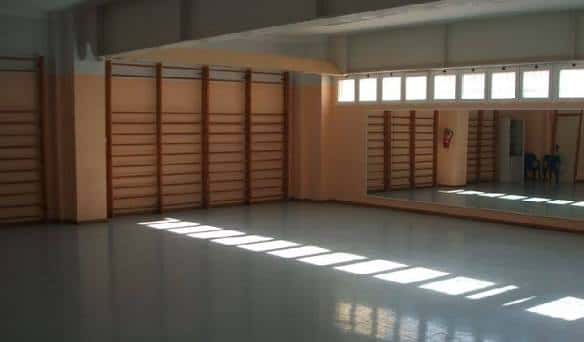 Espacio interior amplio con suelo pulido y espejos, ideal para actividades