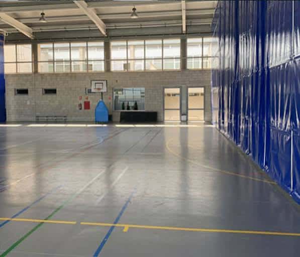 Pabellón deportivo interior con canchas marcadas y gradas laterales