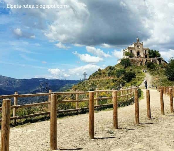 Ermita de Sant Ramon en lo alto de una colina verde con sendero y valla de madera