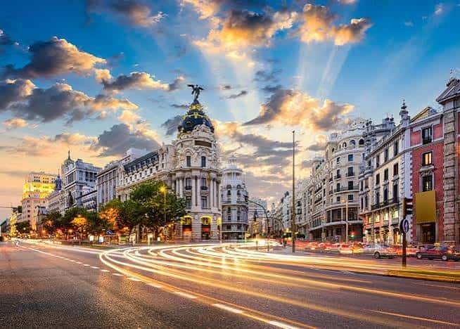 Atardecer en la Gran Vía con estelas de luz de los vehículos y el cielo dramático