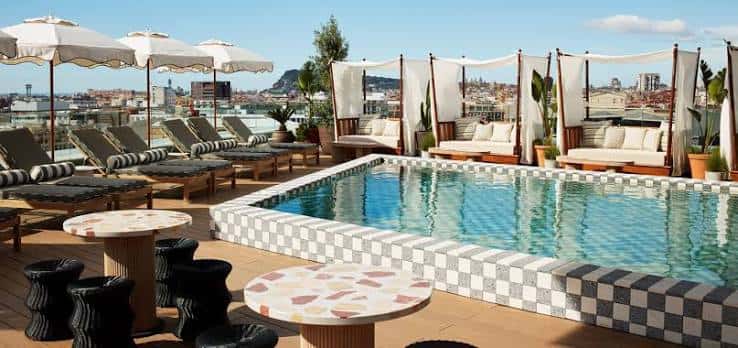 Vista panorámica de la piscina y zona de descanso en la azotea con vistas a Barcelona