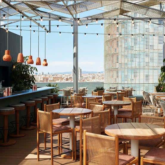 Interior del bar en la terraza con mesas de madera y vista al mar
