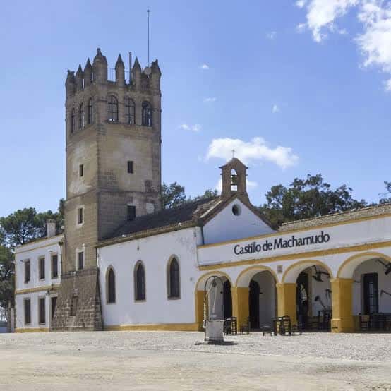 Vista frontal del Castillo de Macharnudo con su torre y fachada blanca bajo cielo azul