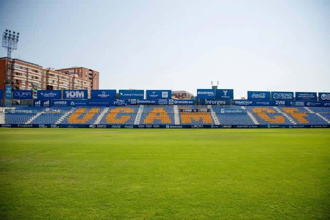 Gradas del estadio con el nombre 'UCAM' en letras amarillas sobre asientos azules