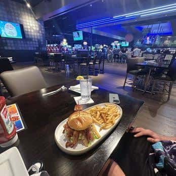 Interior del restaurante con mesas, comida y pantallas deportivas